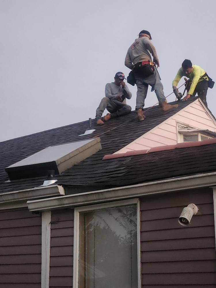 Three roofers working on a steep roof
