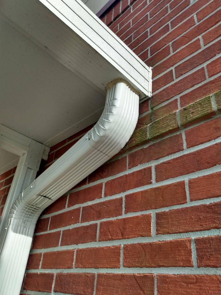 White seamless gutter and downspout on a brick home
