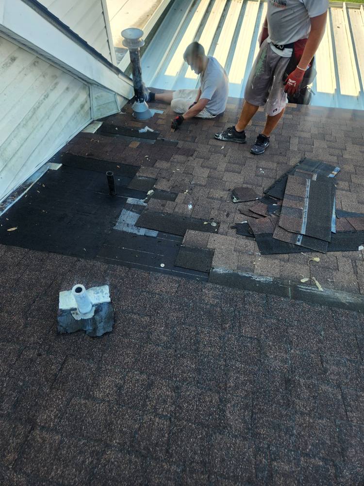Crew replacing damaged shingles around a vent