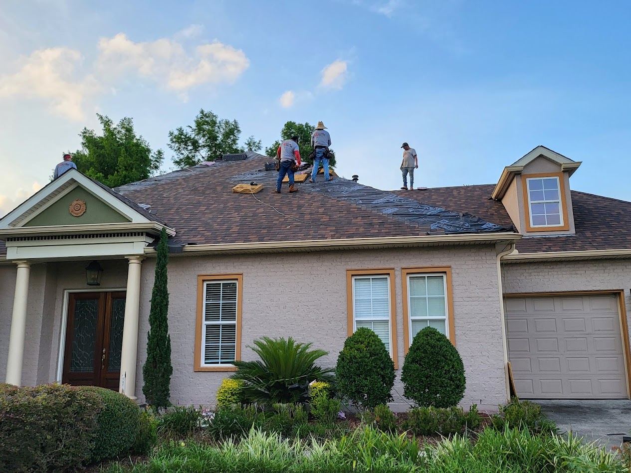 Our crew in branded shirts replacing the shingle roof on a brick New Orleans home